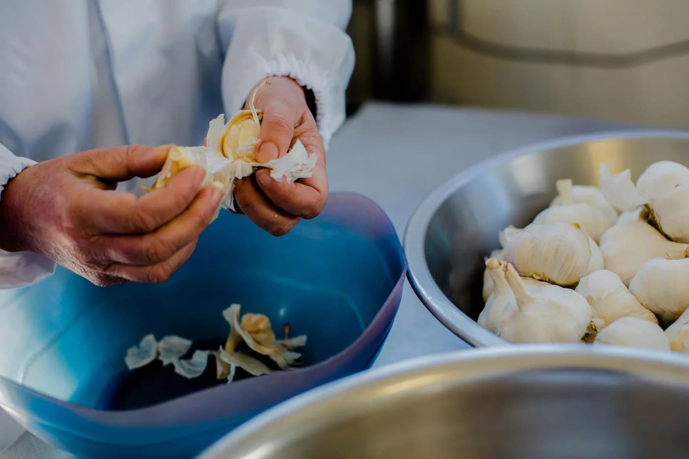 Kitchen staff peeling garlic by hand in a commercial kitchen